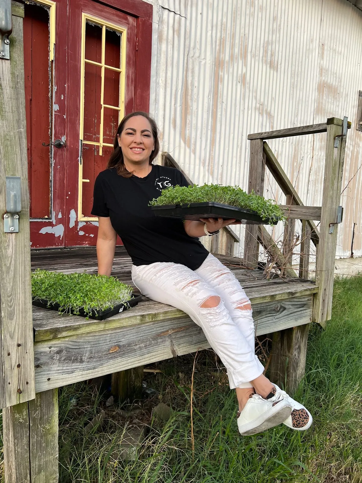 Brooke holding fresh trays of Teeny Greeny microgreens