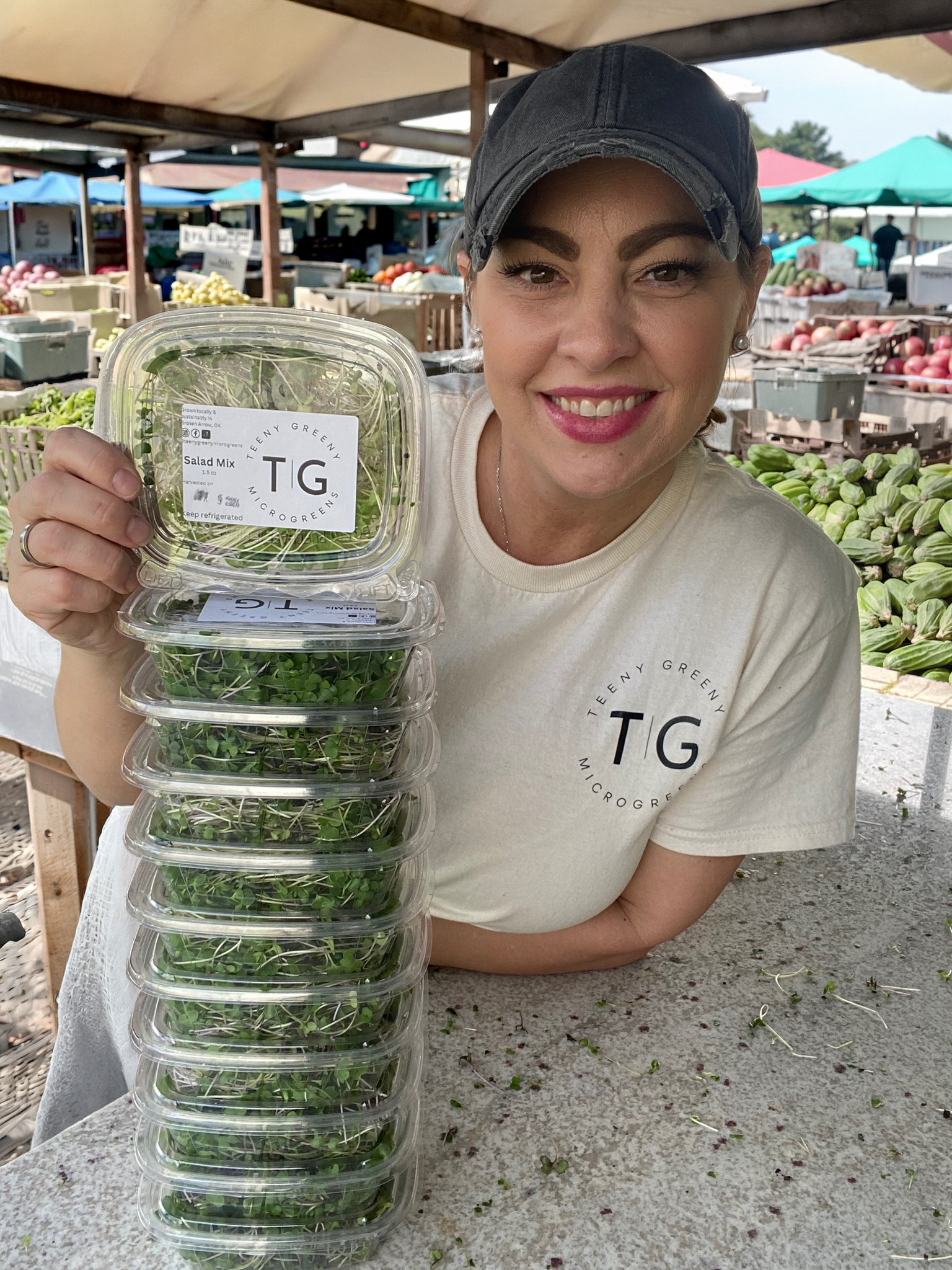 Brooke holding a stack of Teeny Greeny containers at the market